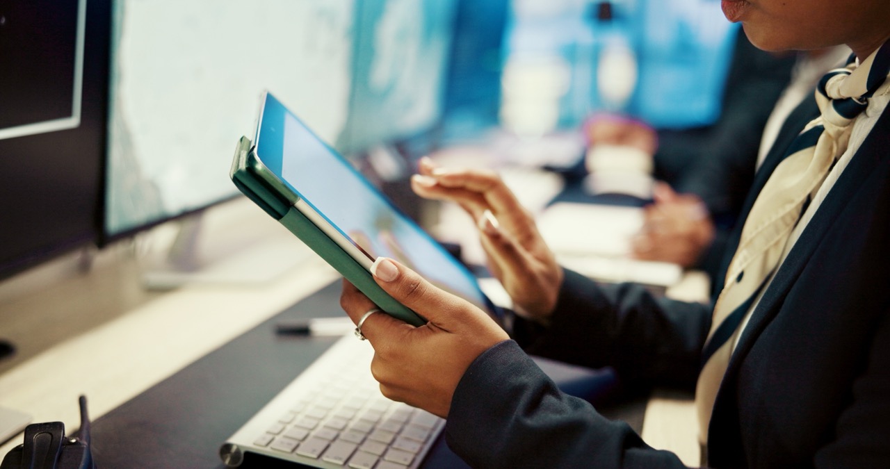 A person sitting at their desk swipes on a tablet.